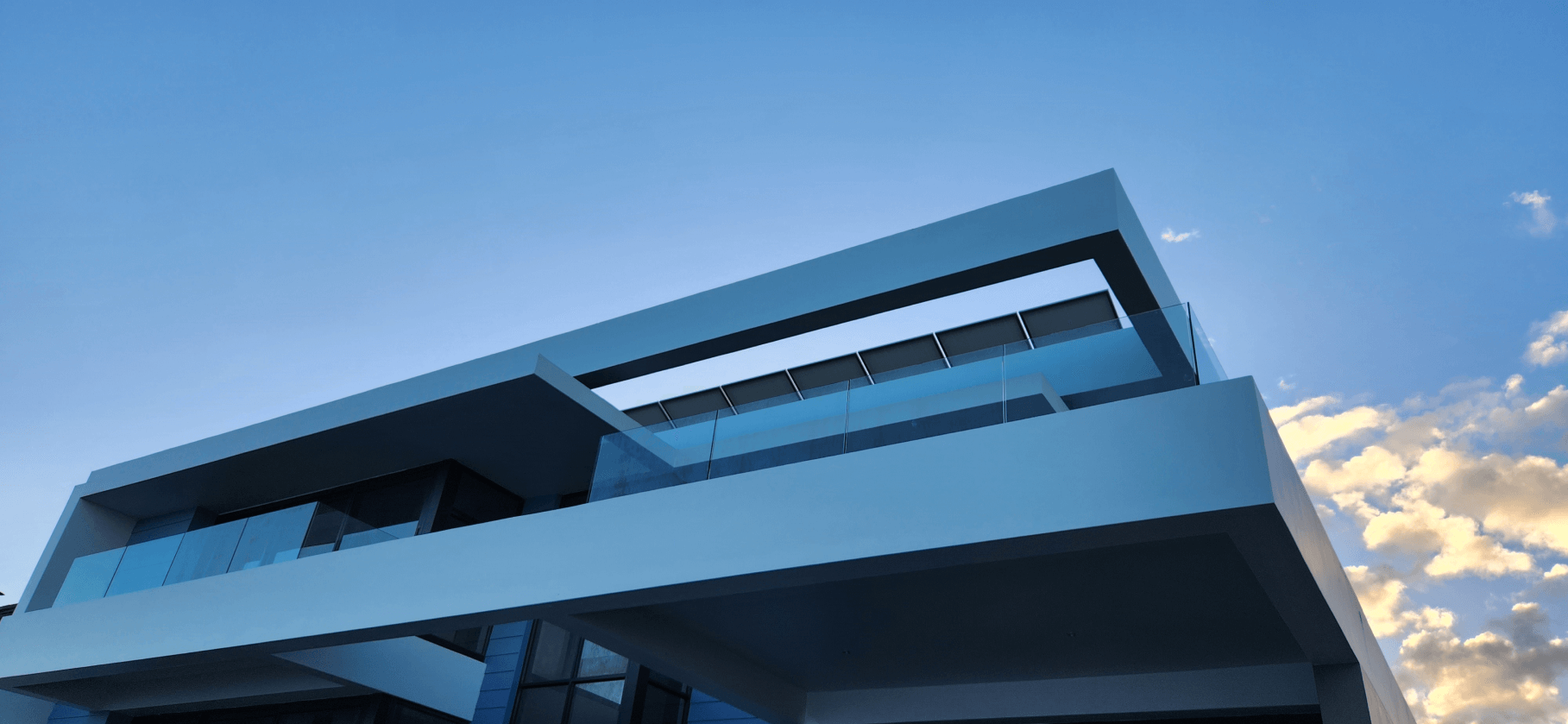 Ground view of beautiful home with glass balustrade - alufox